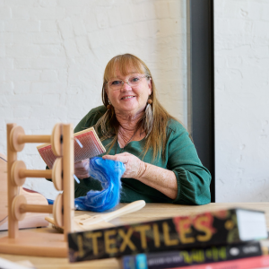 Woman smiling and working on textile craft